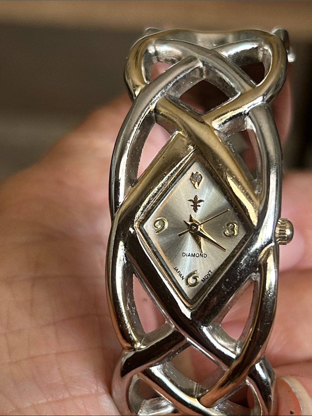 Cato brand women's cuff-style analog watch with a fleur-de-lis diamond dial